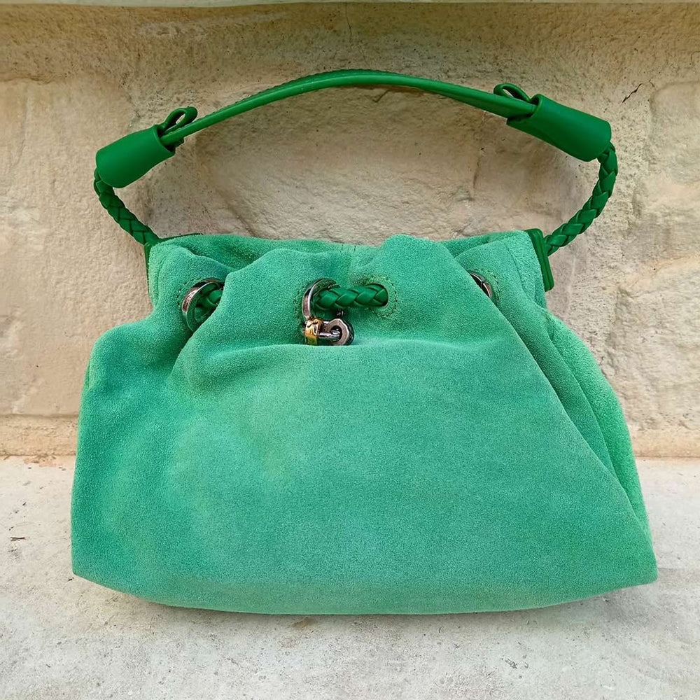 Green suede bag on a textured beige surface